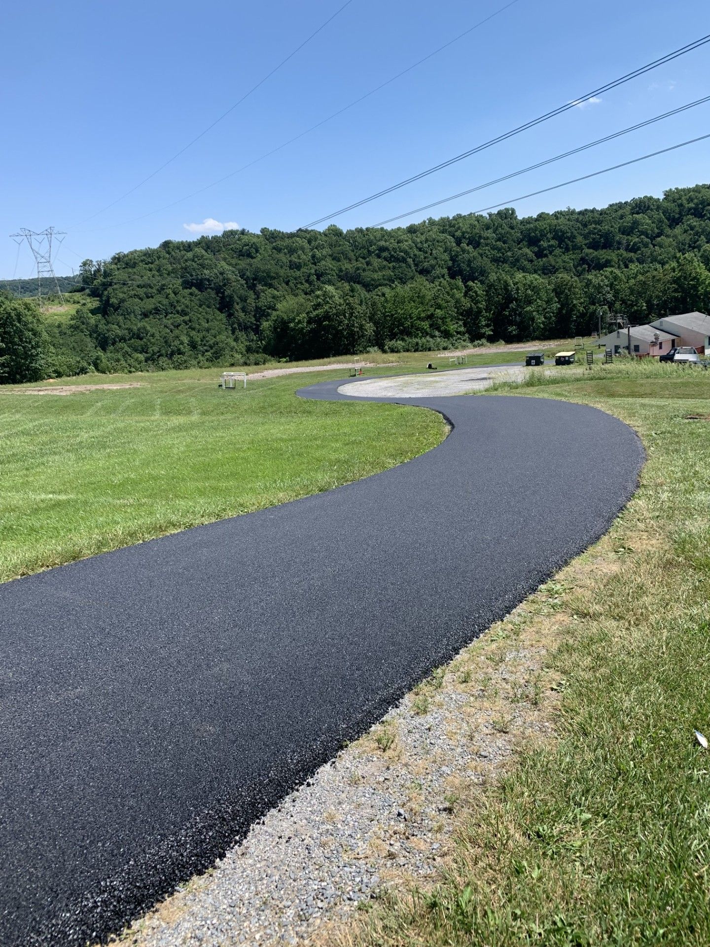 A curvy road going through a grassy field.