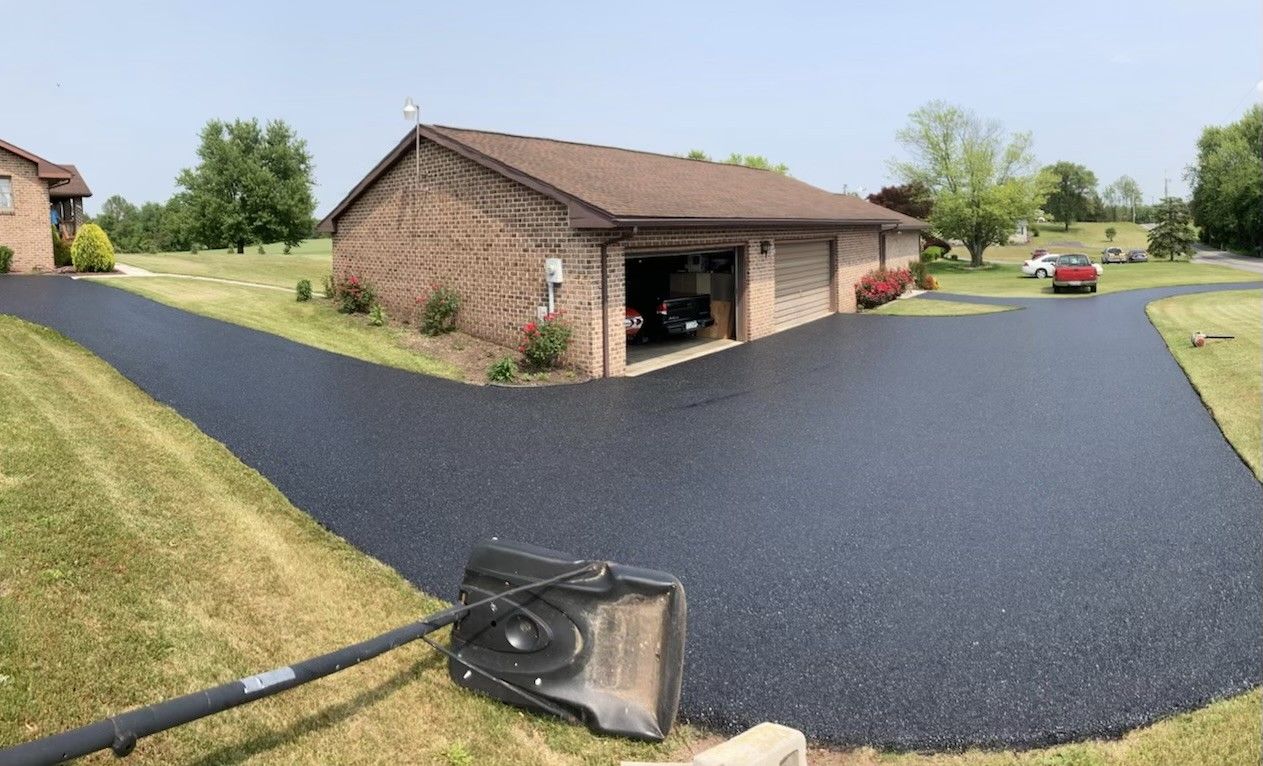 A driveway is being paved in front of a house and garage.