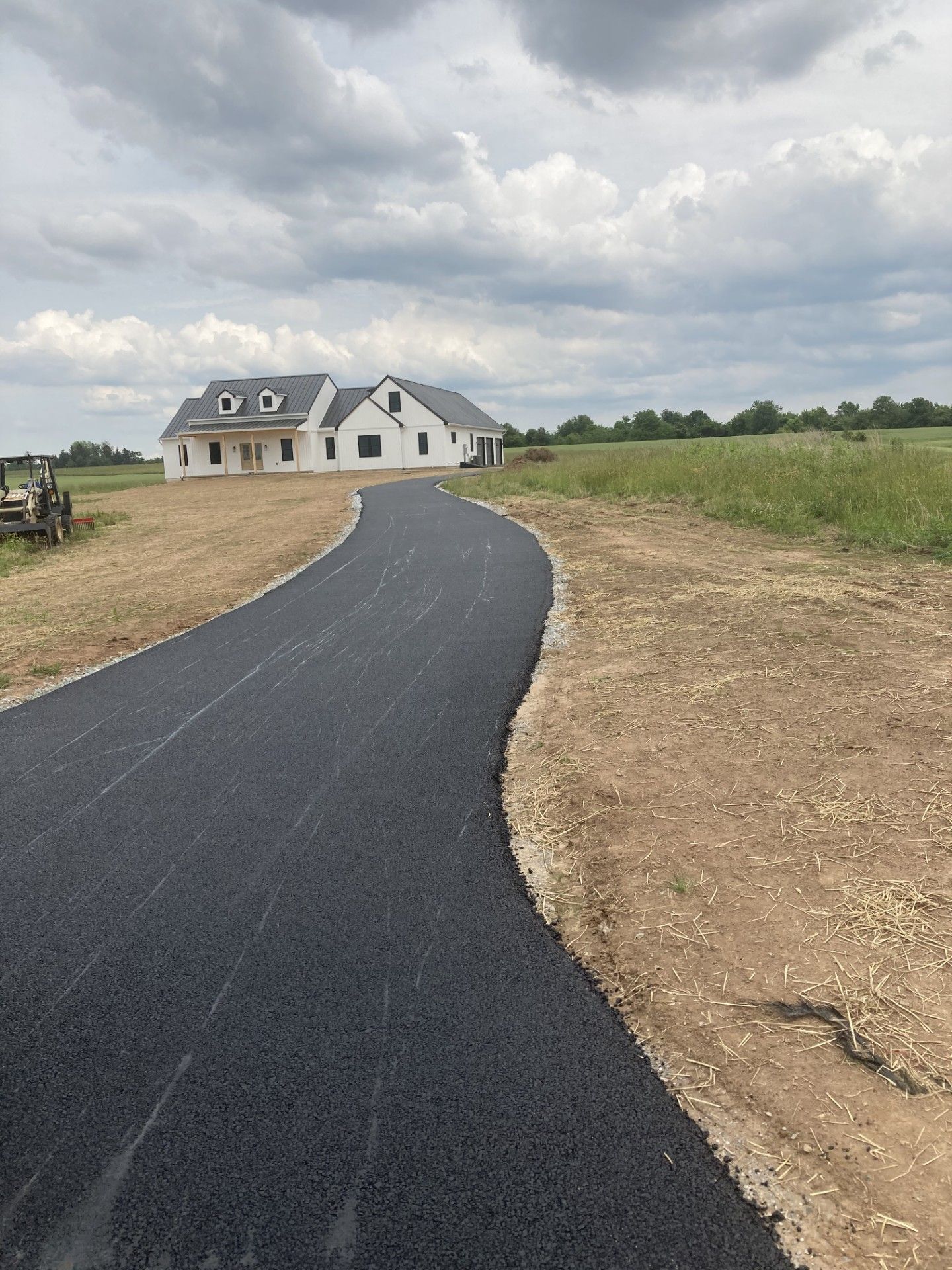A road leading to a house in the middle of a field.