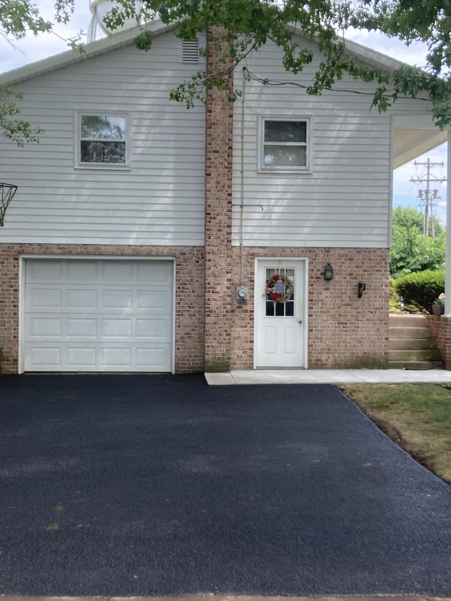 A white house with a brick wall and a white garage door
