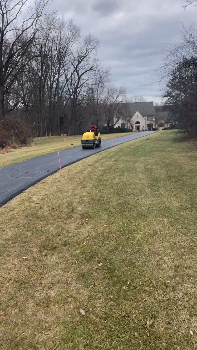 A yellow car is driving down a road next to a house.