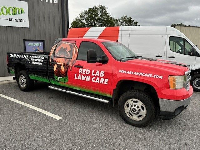 A red lab lawn care truck is parked in a parking lot