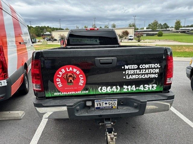 A black truck with a sticker on the back that says weed control fertilization landscaping