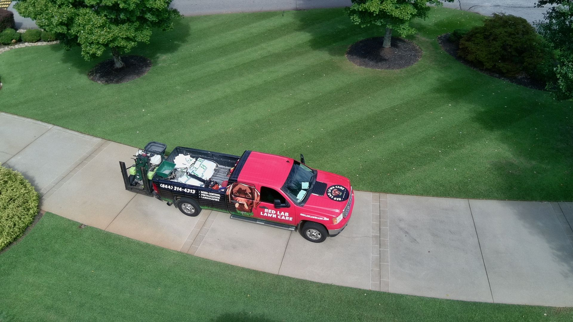 An aerial view of a red truck driving down a sidewalk.