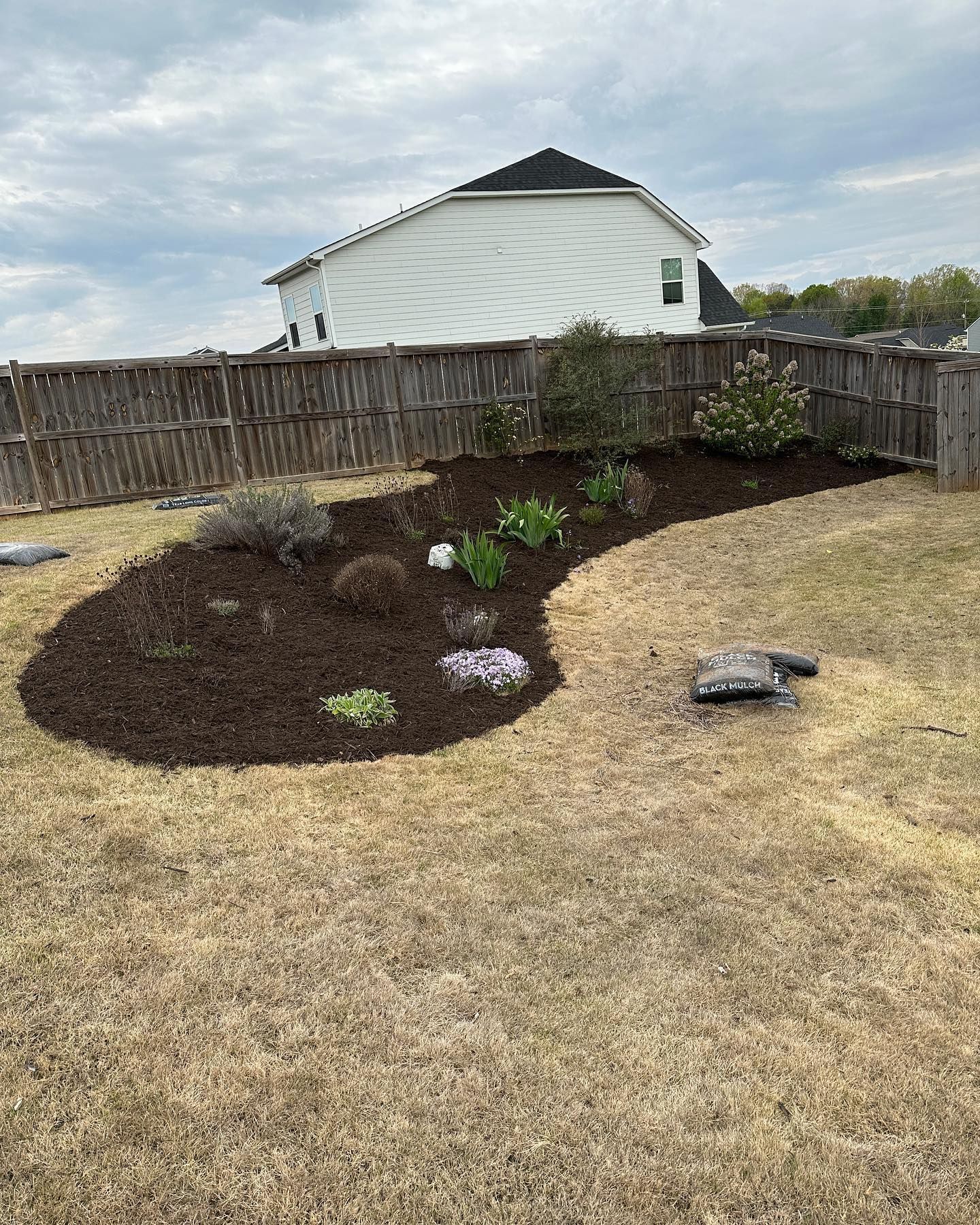 A backyard with a fence and a garden in the middle of it.