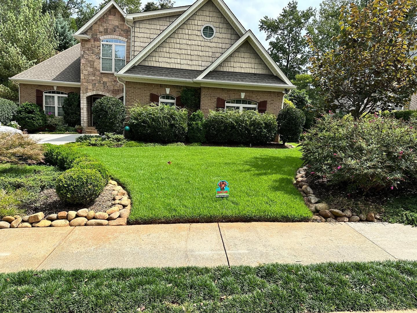 A large brick house with a lush green lawn in front of it.