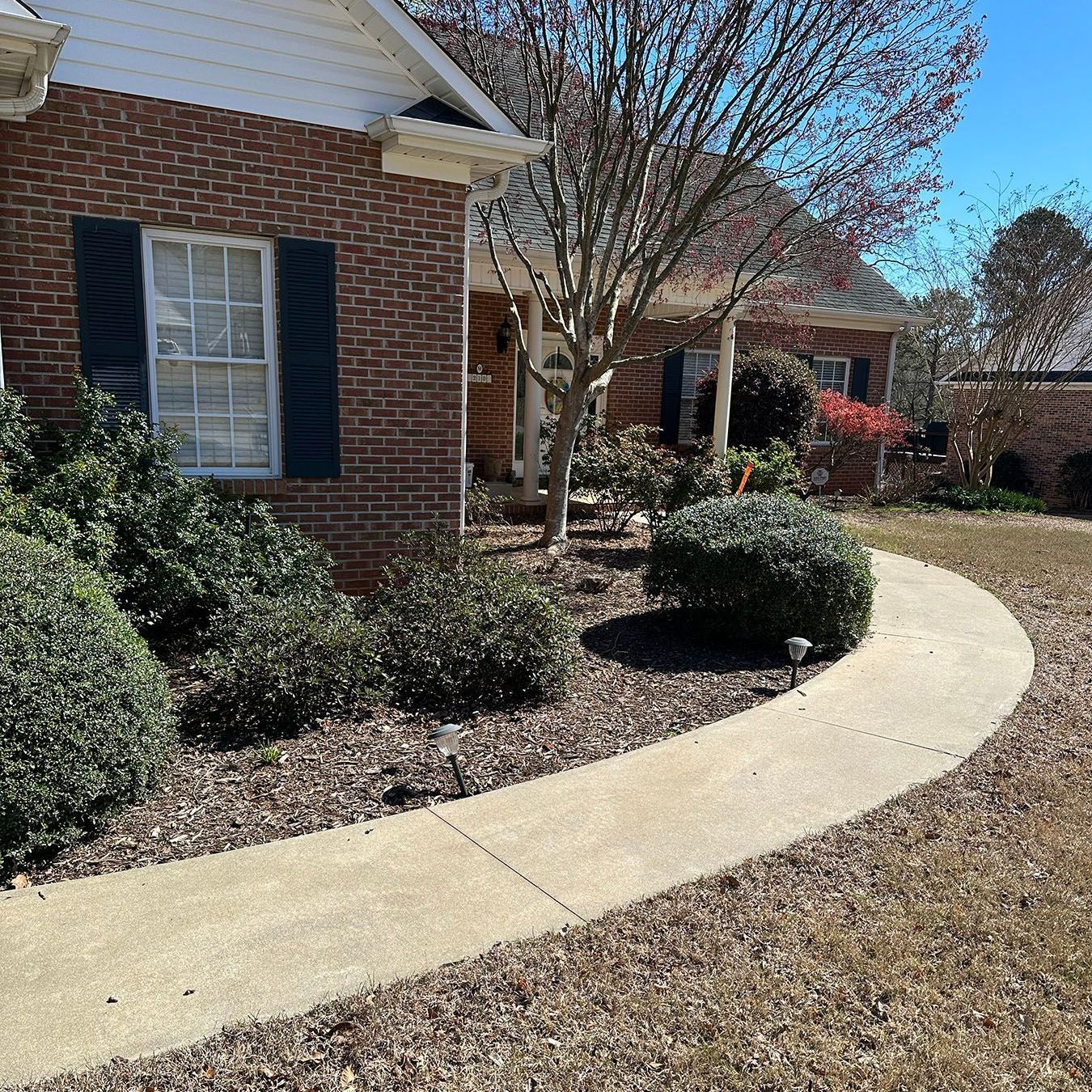 A brick house with a concrete walkway leading to it.