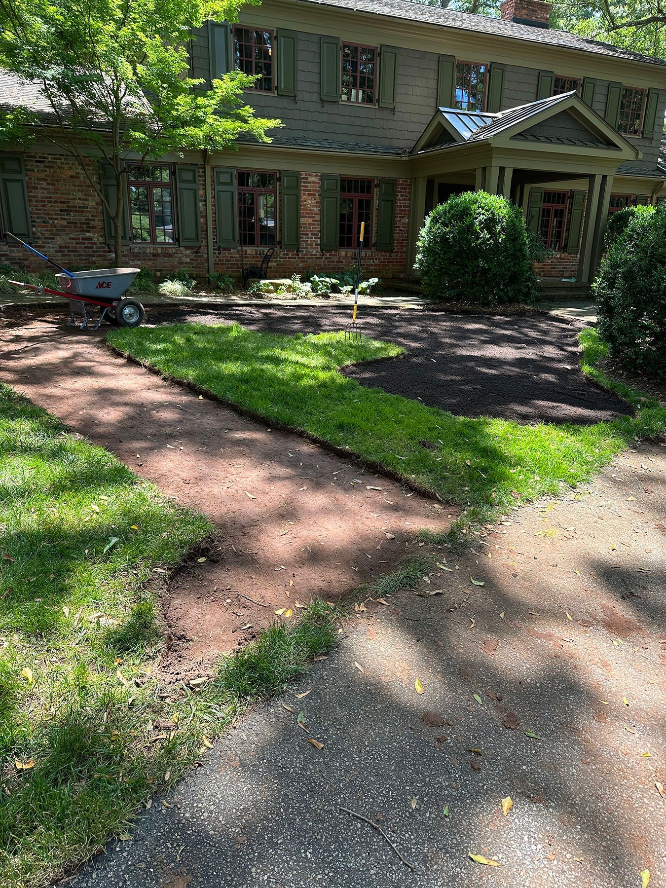 A house with a driveway and a lawn mower in front of it.