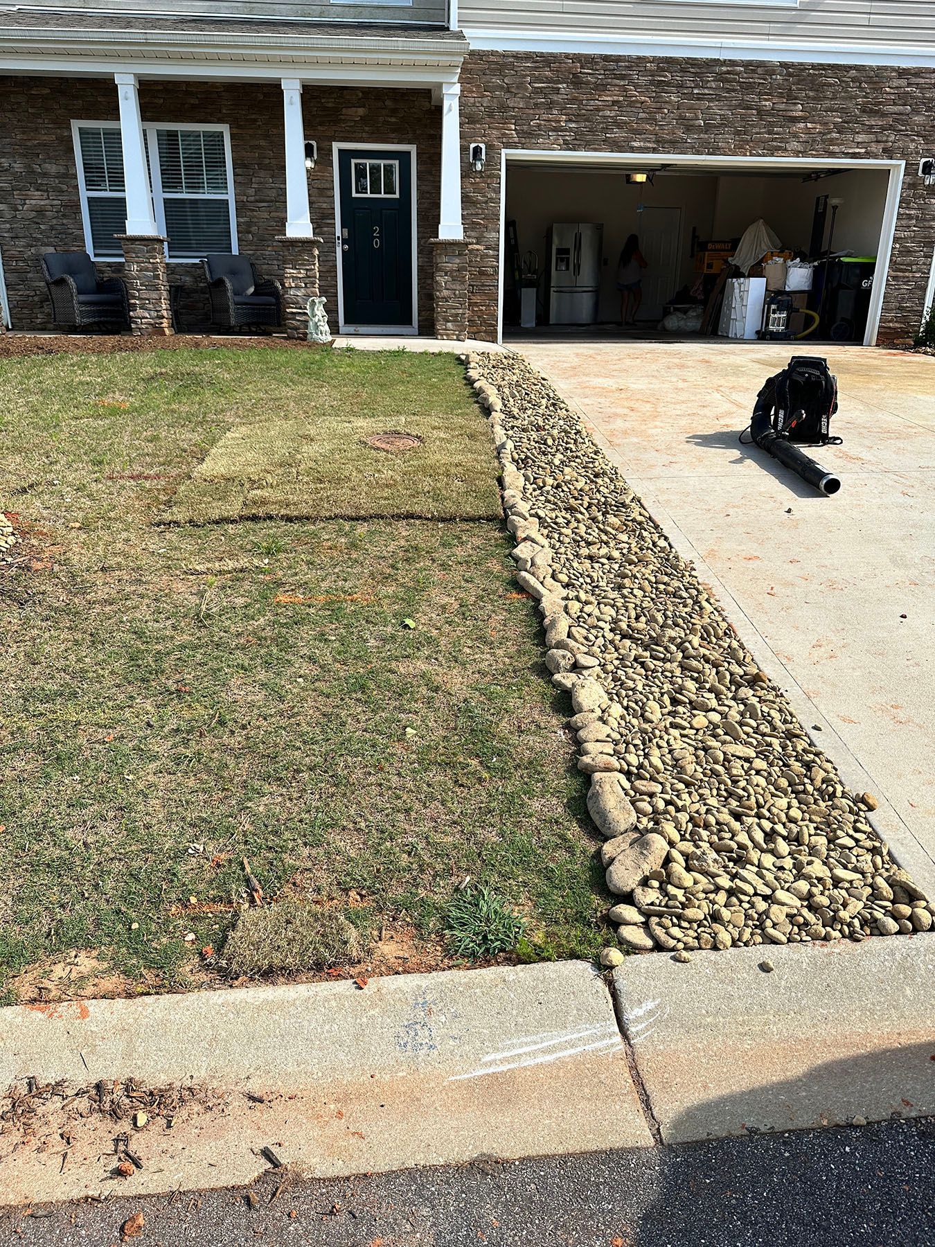 A dog is sitting on the sidewalk in front of a house.