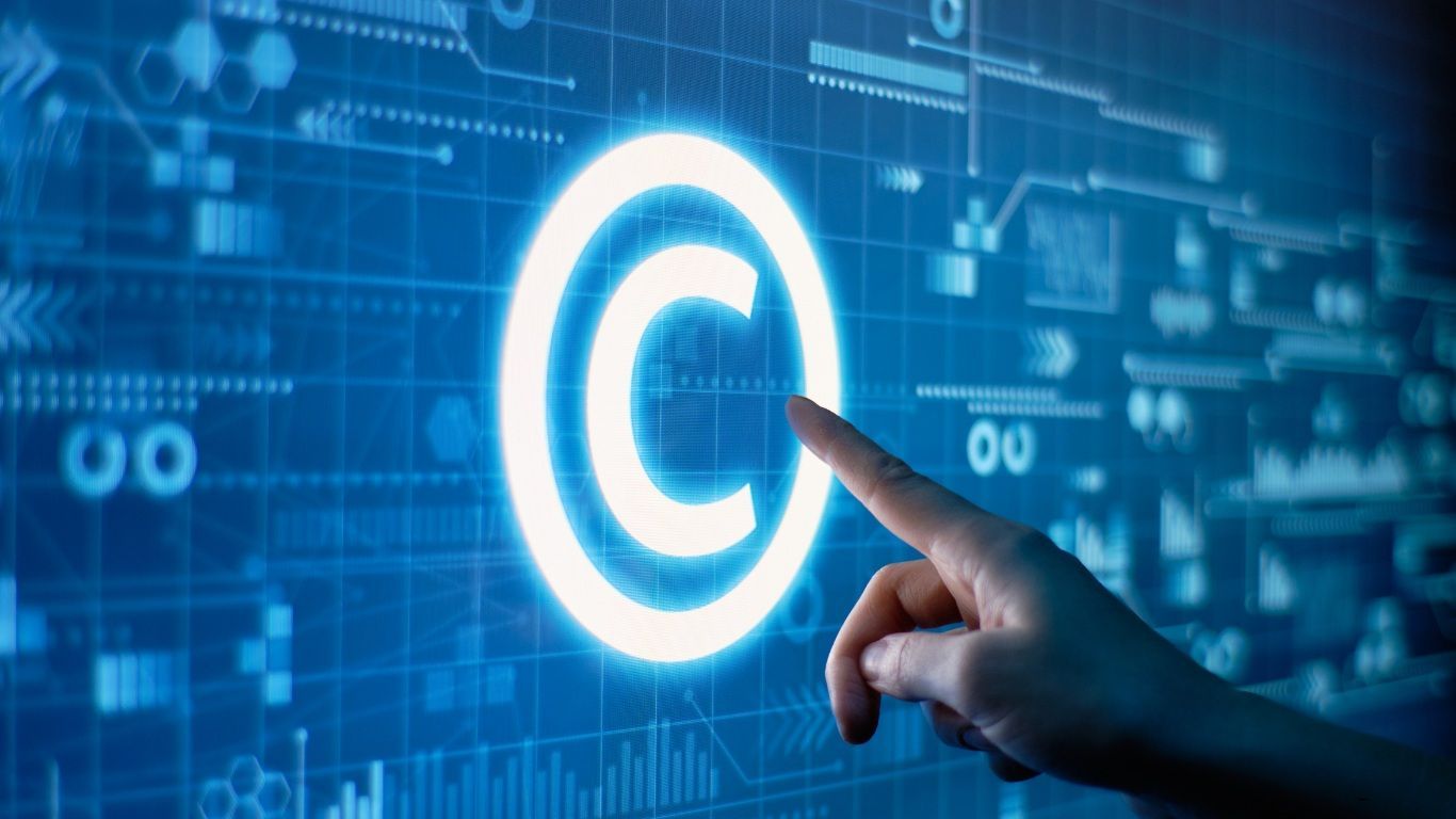 Hand touching a glowing copyright symbol on a blue digital interface.