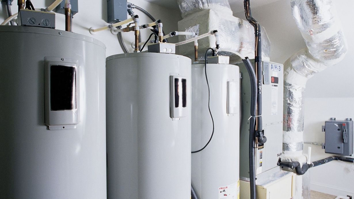 Water treatment system in a basement with tanks, pipes, and a water heater.