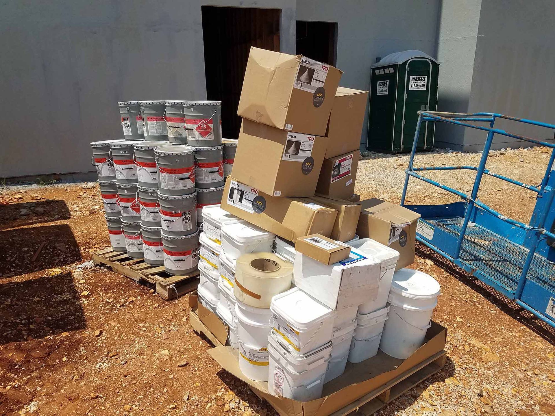 A pile of boxes and buckets on a pallet in front of a building.