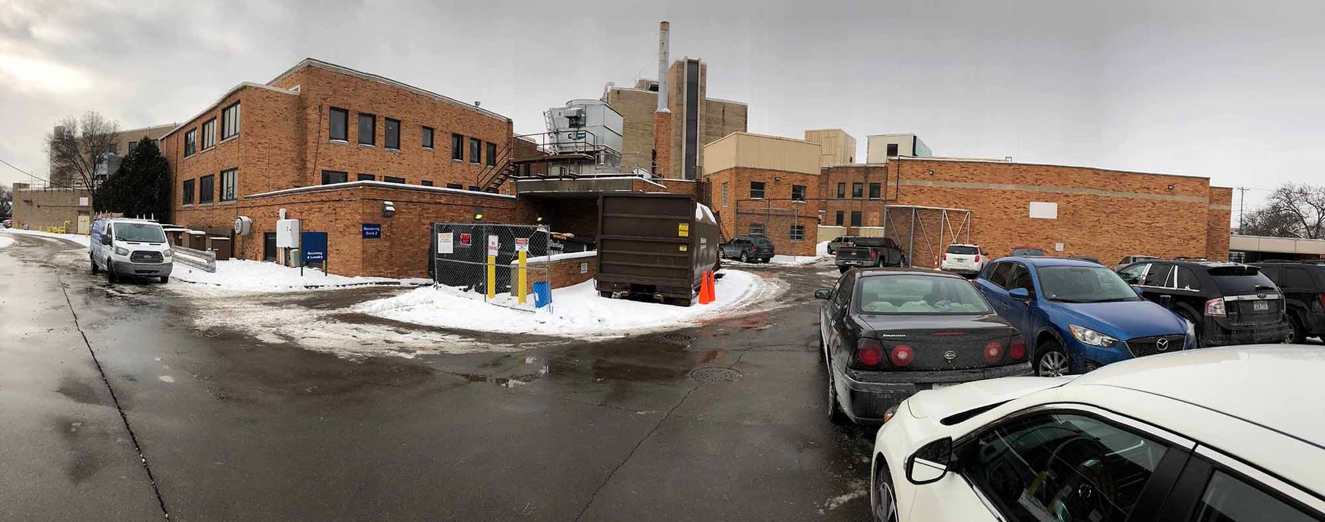 A parking lot with cars parked in front of a building in the snow.
