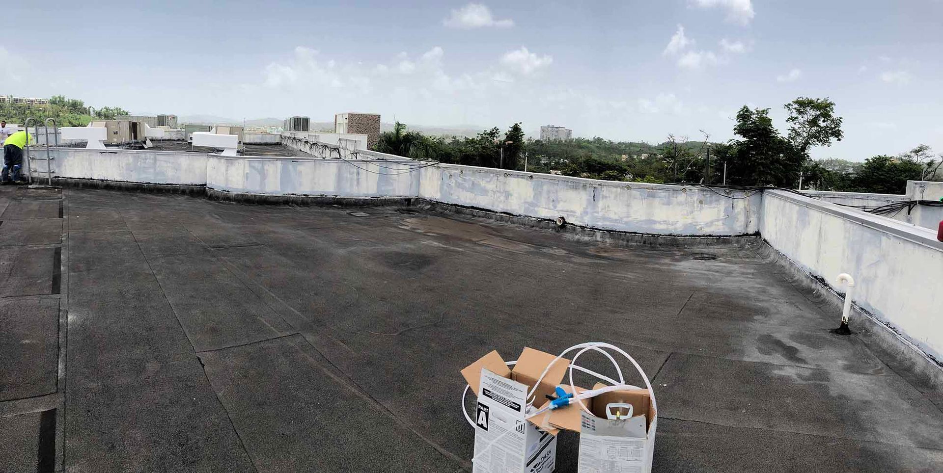 A man in a yellow vest is standing on the roof of a building.