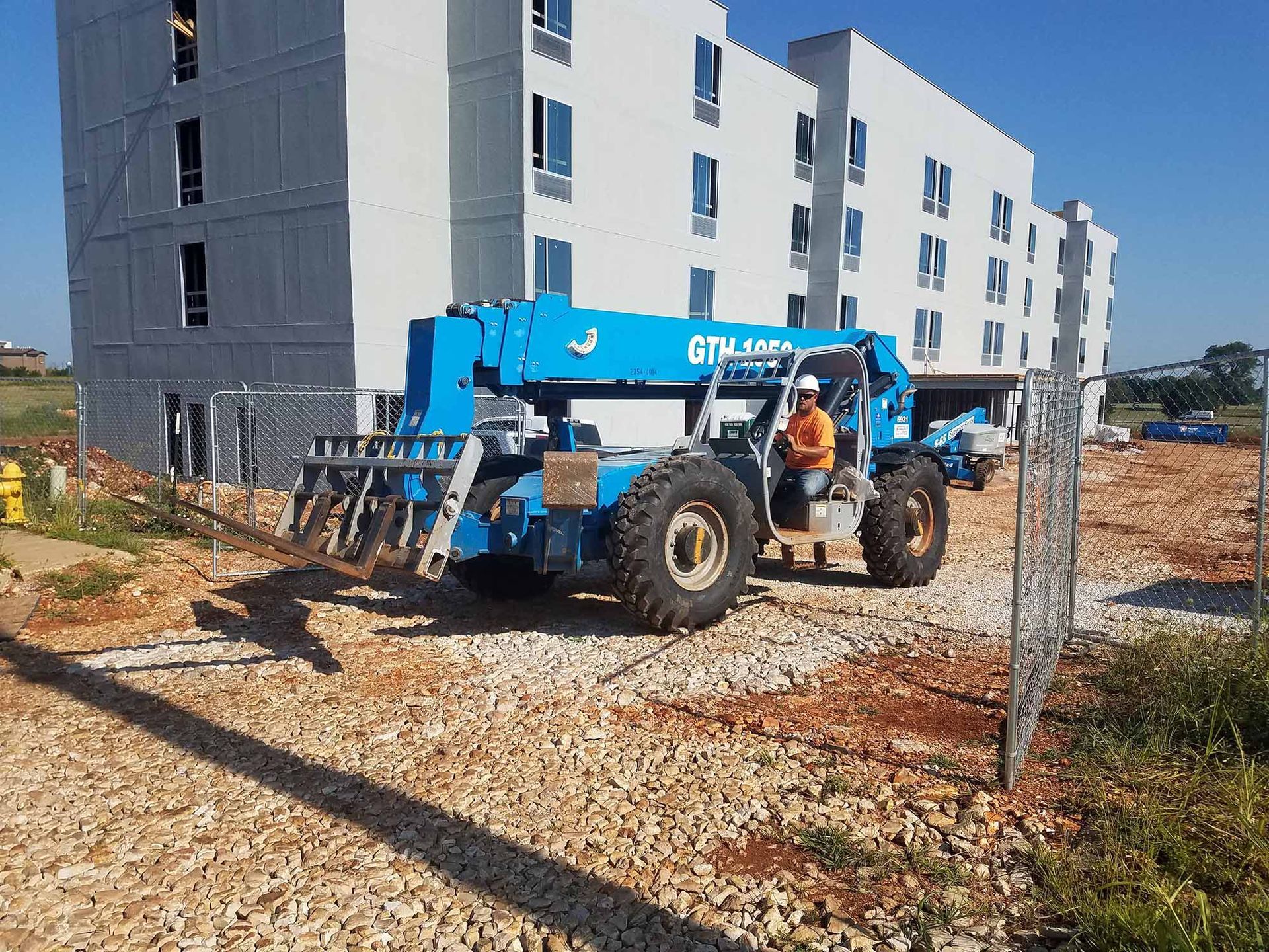 A blue forklift is parked in front of a building under construction.