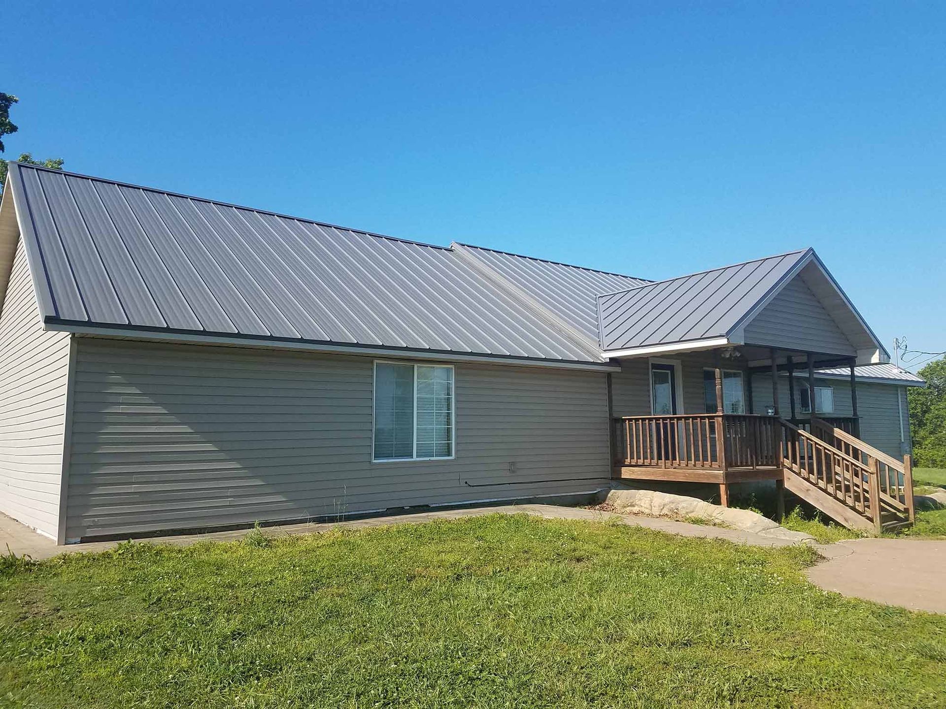 A house with a metal roof is sitting on top of a lush green field.