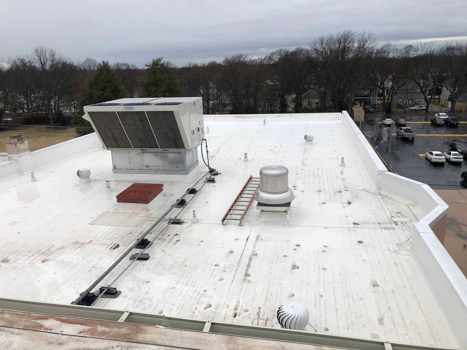 The roof of a building with a white roof and a ladder on it.