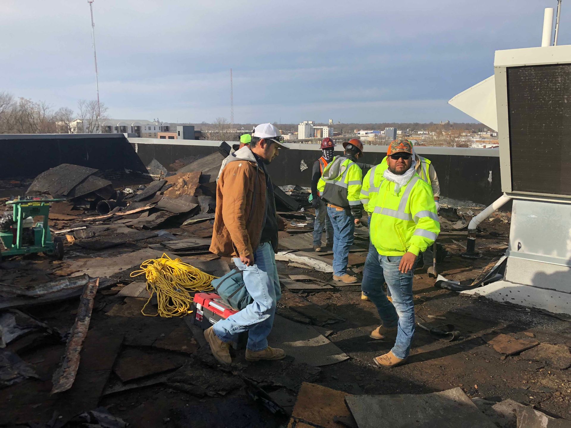 A group of construction workers are standing on top of a roof.