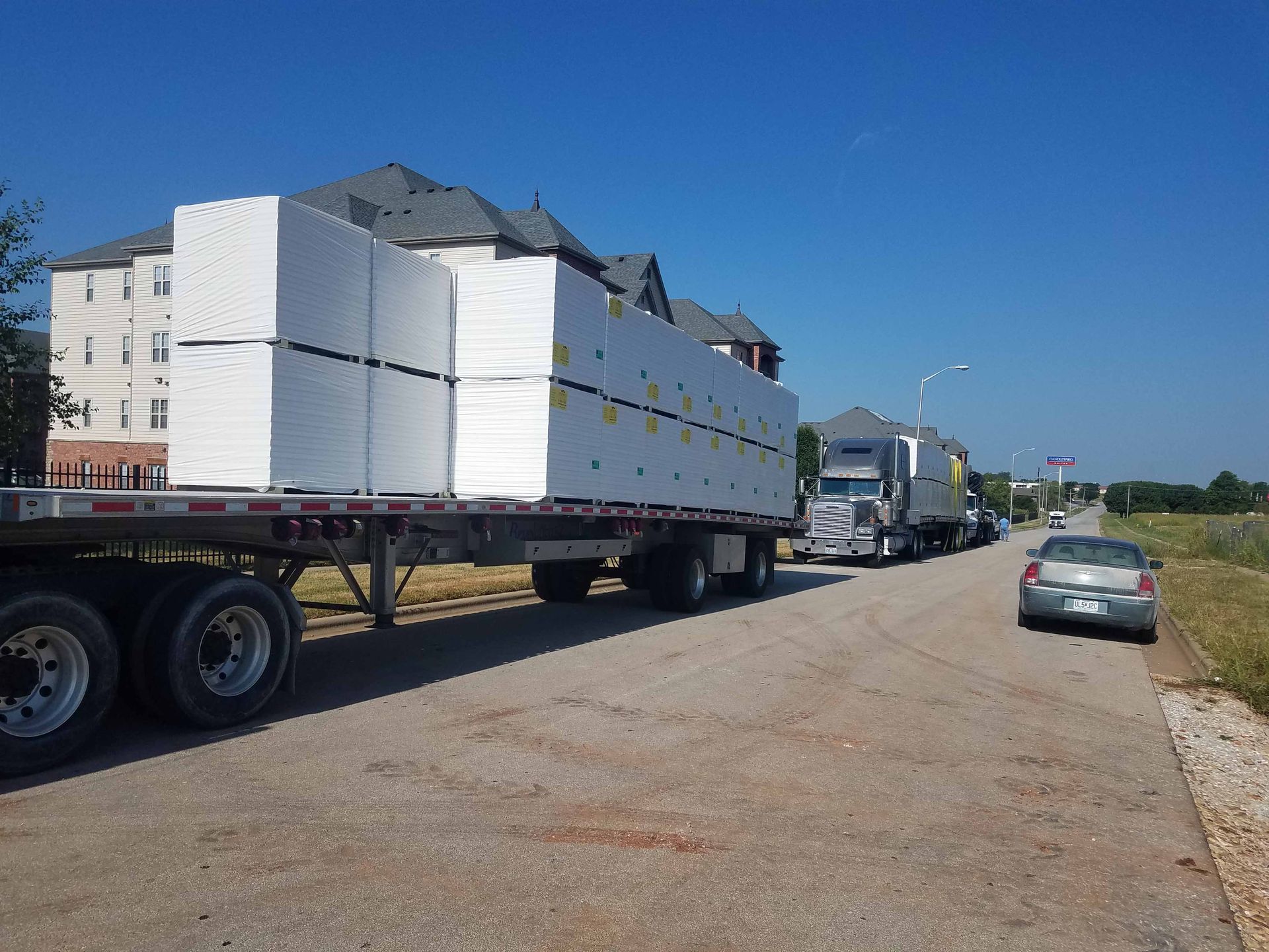 A semi truck is carrying a load of styrofoam blocks down a street.
