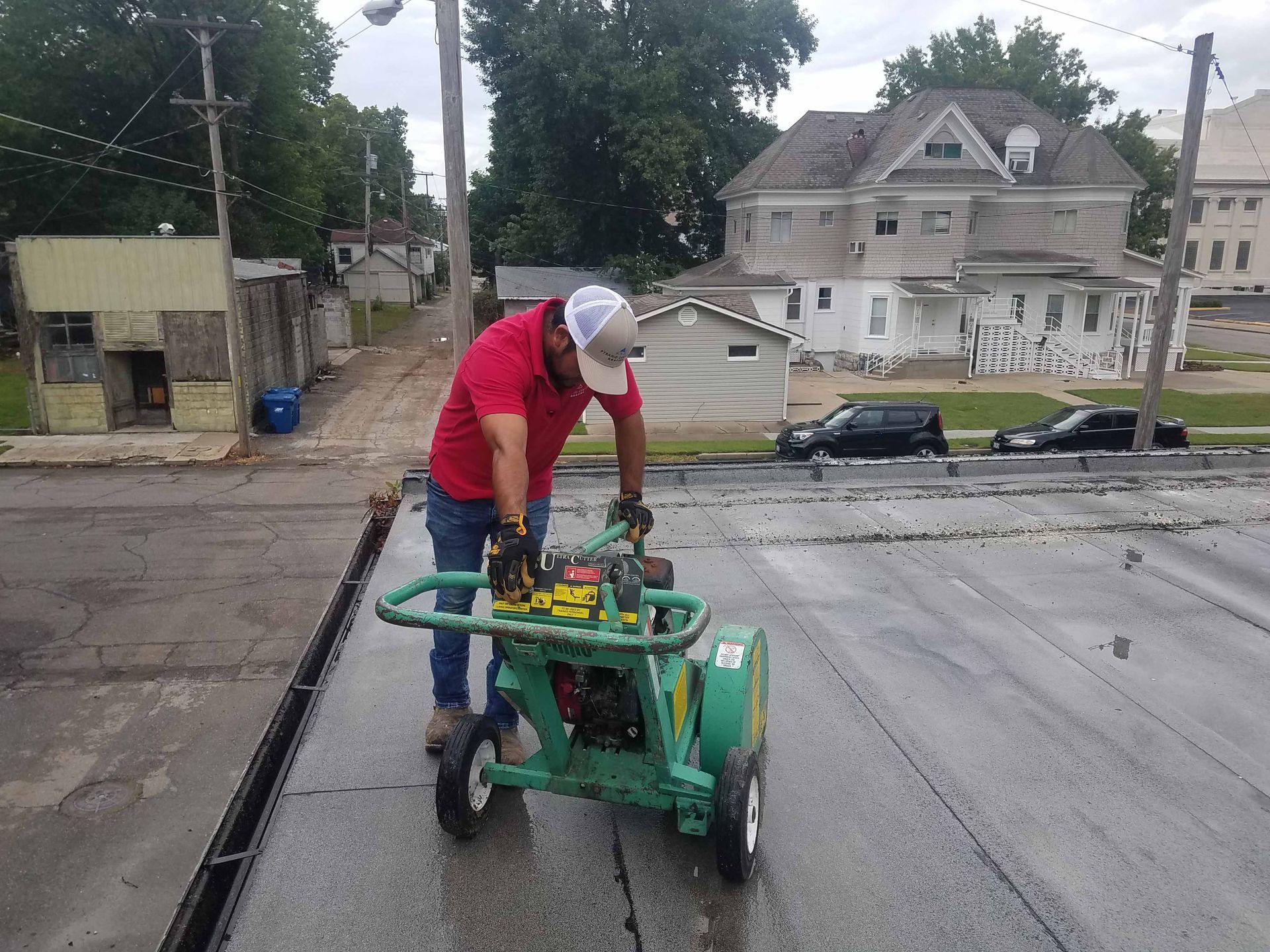 A man in a red shirt is working on a green machine