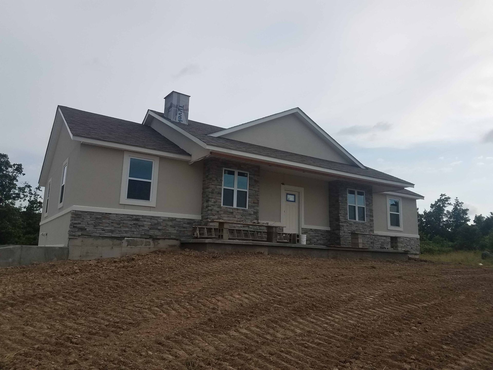 A large house is sitting on top of a dirt field.
