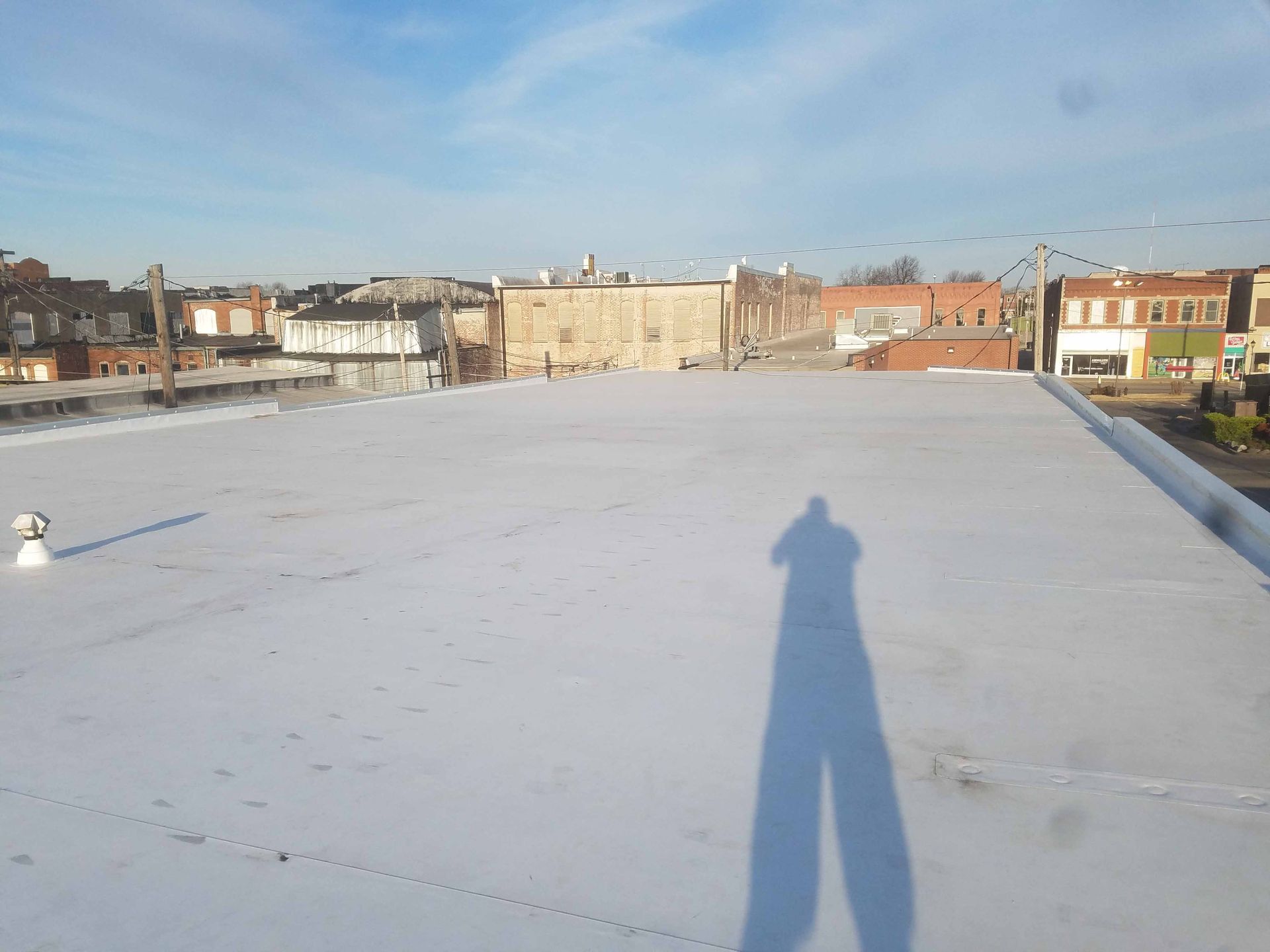 A shadow of a person is cast on the roof of a building.