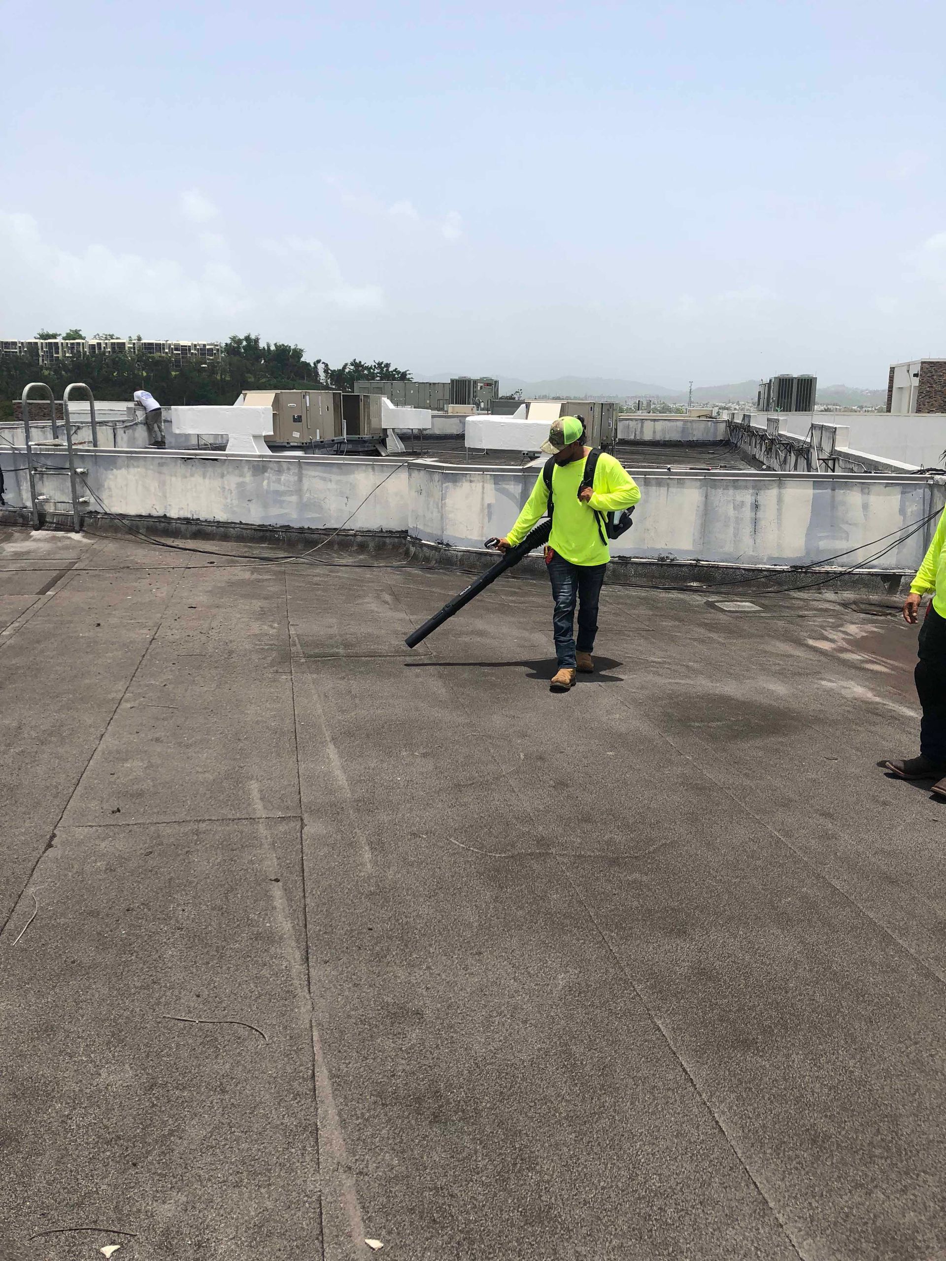 A man is using a blower to clean the roof of a building.