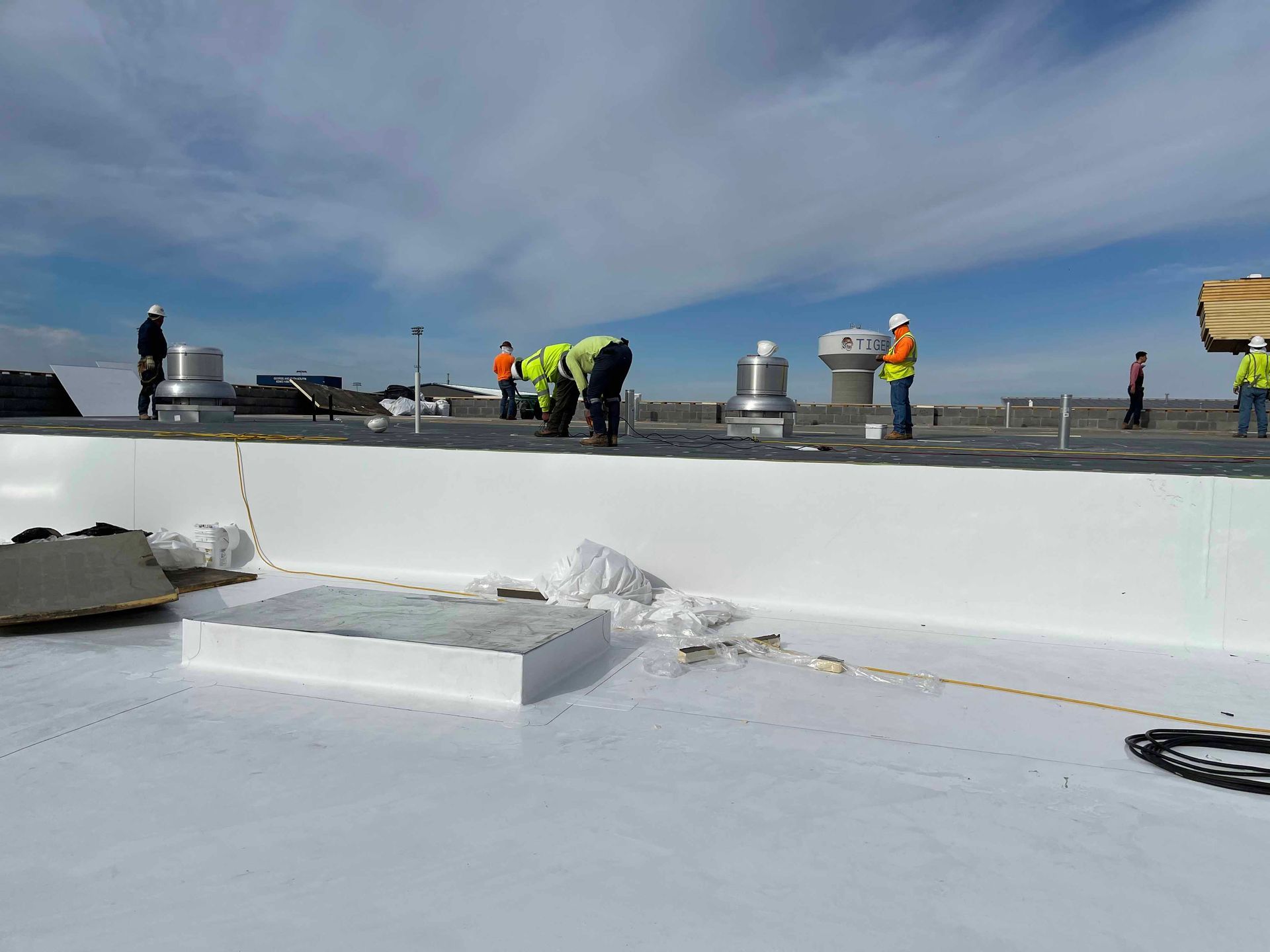 A group of construction workers are working on a white roof.