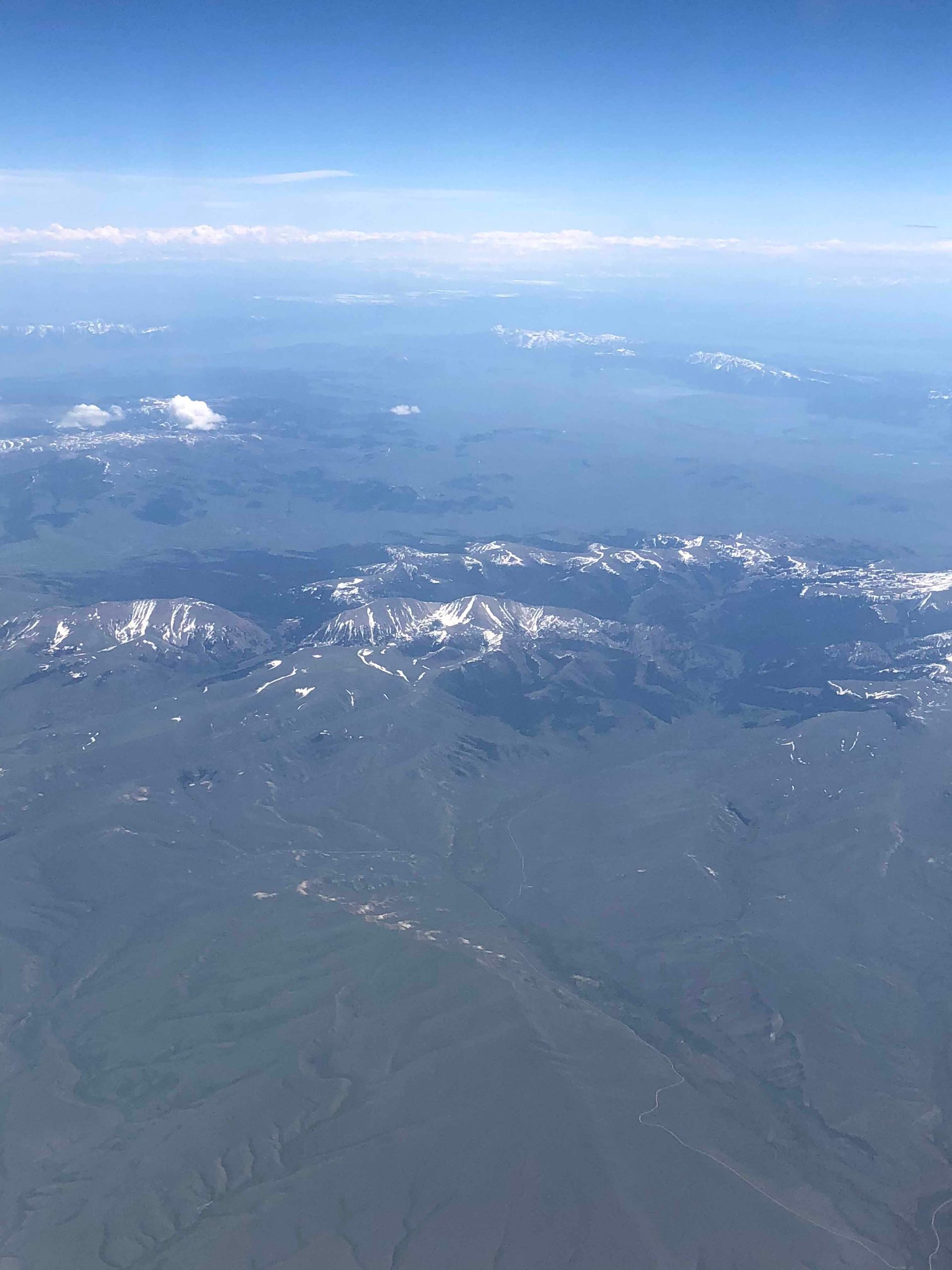 An aerial view of a mountain range from an airplane window.