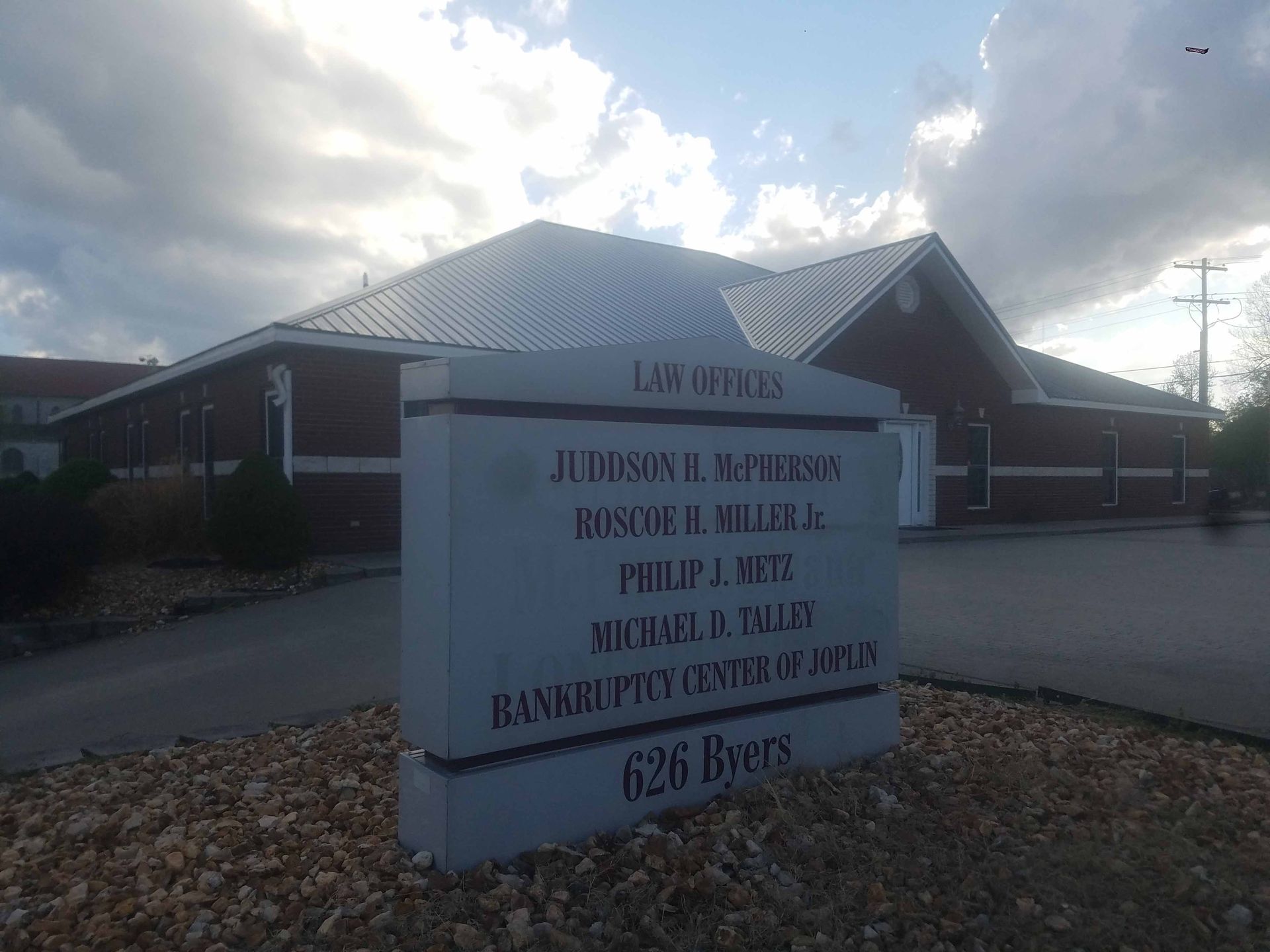 A sign for a law office is in front of a brick building.