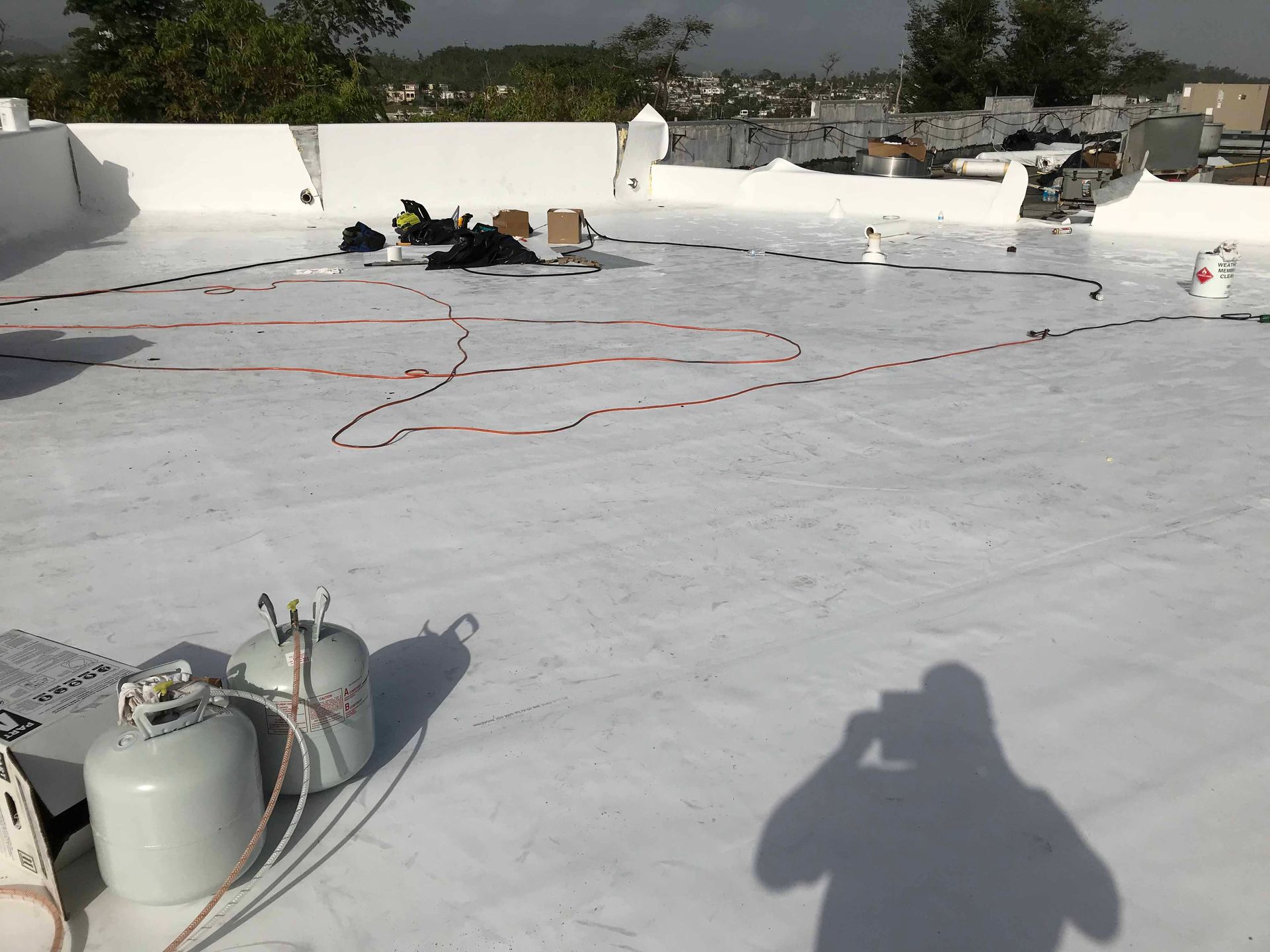 A shadow of a person is cast on a white roof