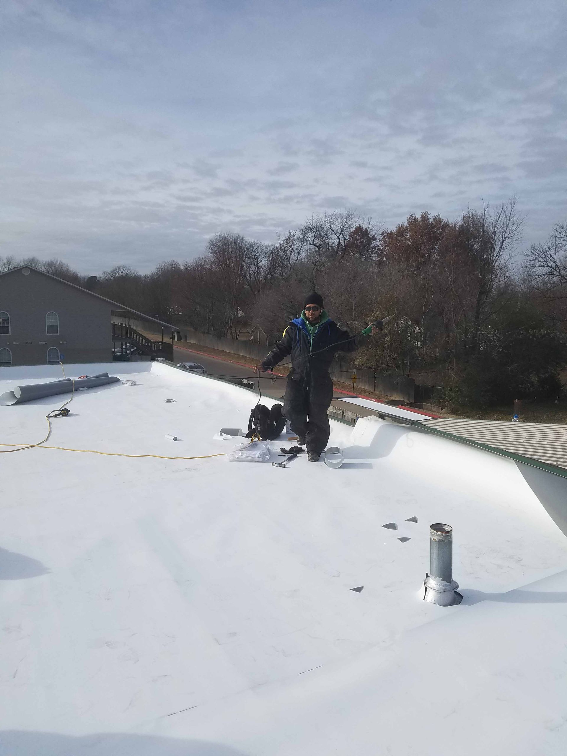 A man is standing on top of a snow covered roof.