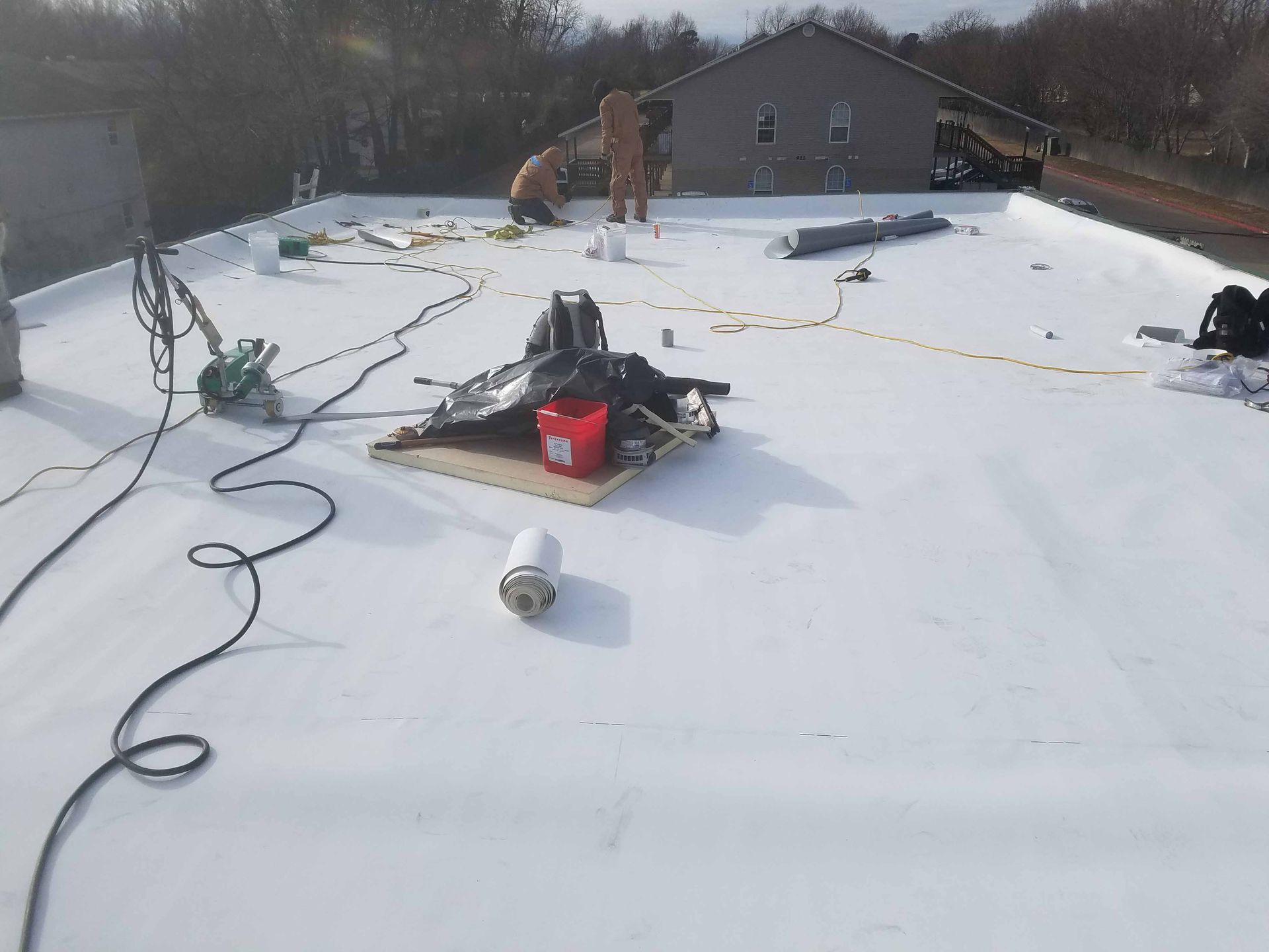 A group of people are working on a white roof.