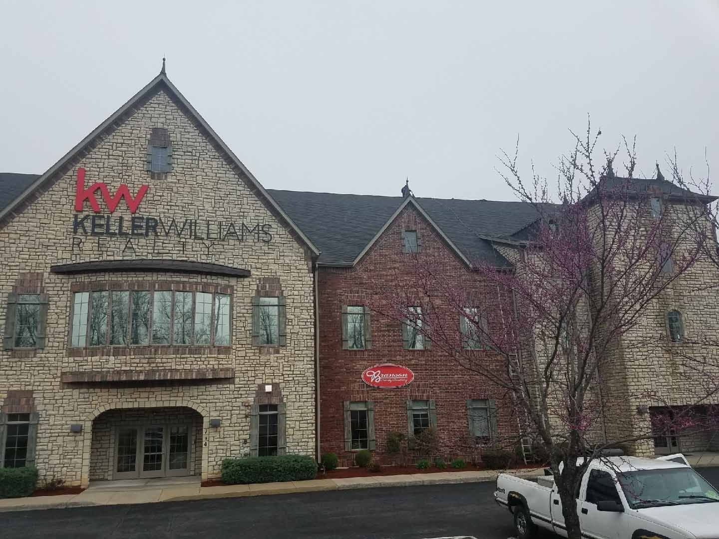 A white truck is parked in front of a large brick building.