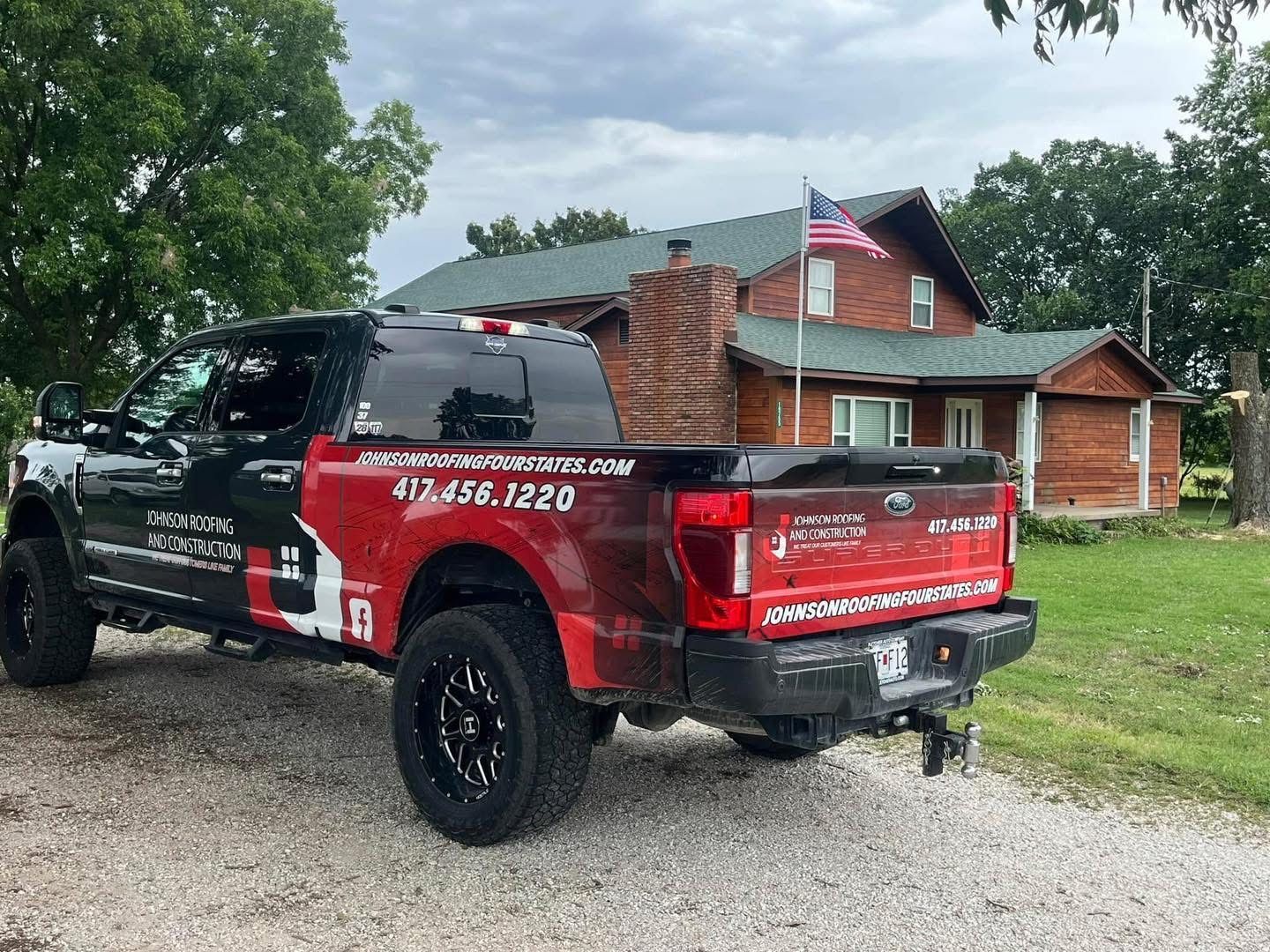 A red truck is parked in front of a wooden house.