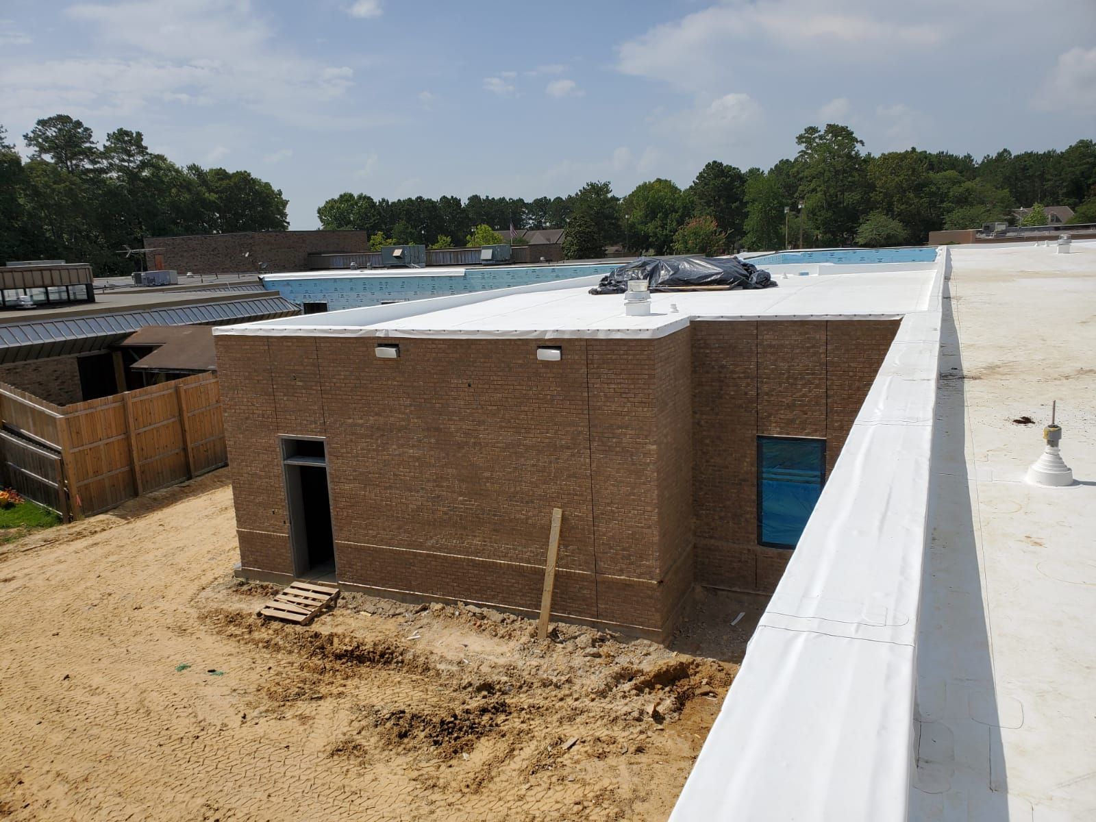 A brick building under construction with a white roof