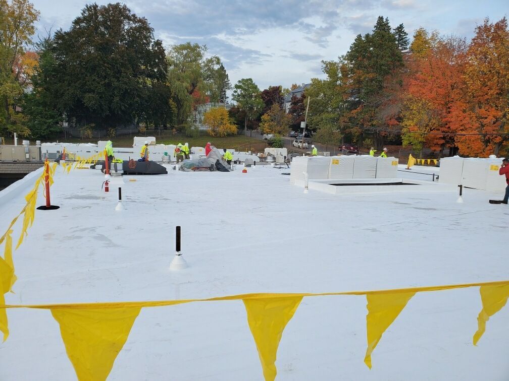 A white roof is being built with yellow flags in the foreground.