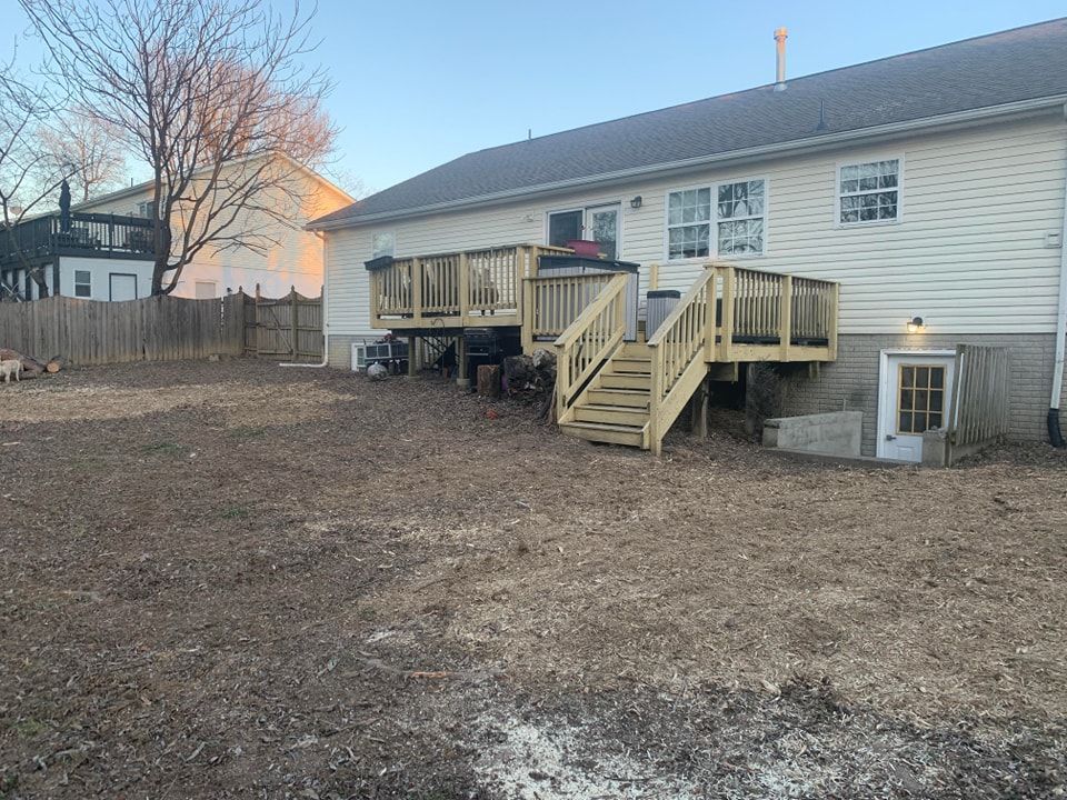 The backyard of a house with a wooden deck and stairs.