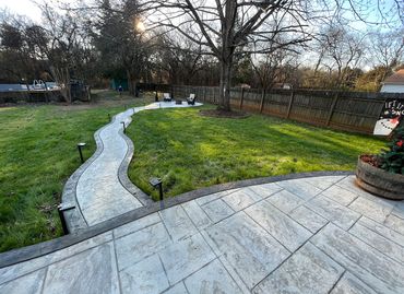 a concrete walkway leading to a lush green yard