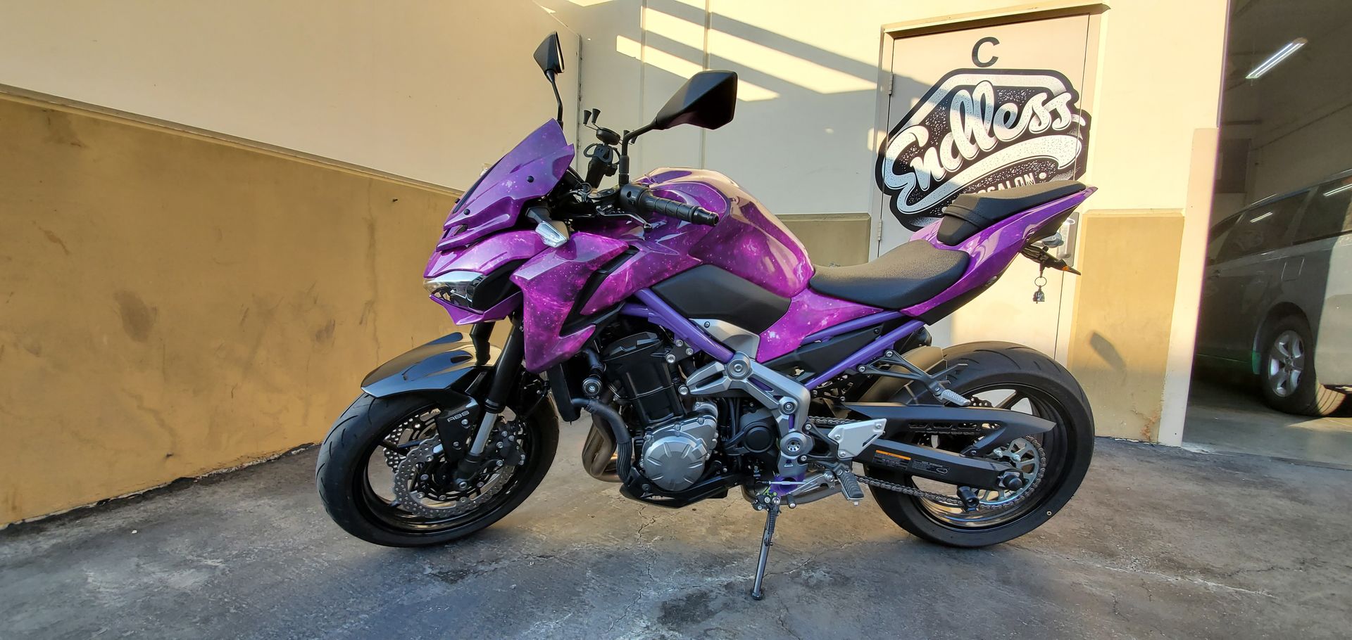 Purple Kawasaki Z900 motorcycle parked in front of a building with graffiti.