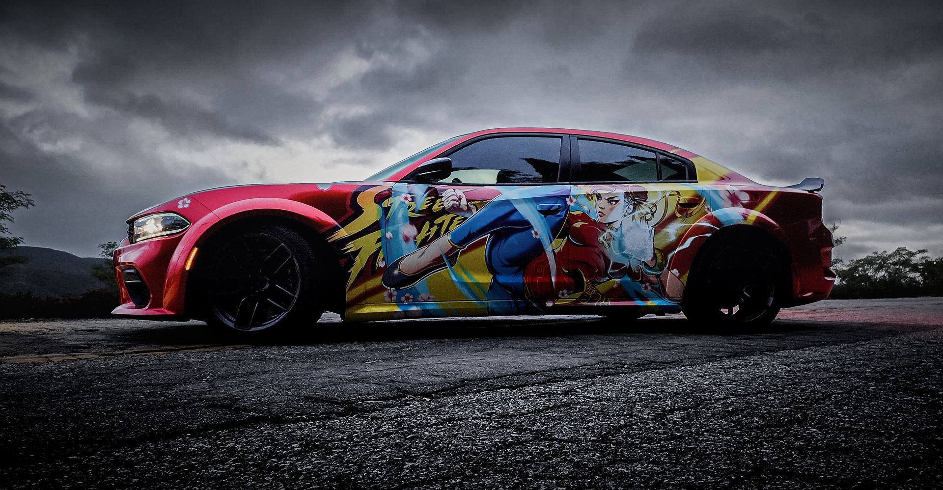 Red car with anime wrap on a dark, overcast day.