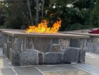 A fire pit made of stone with flames coming out of it