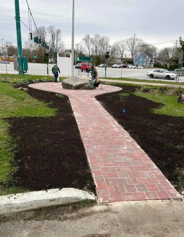 A man is working on a brick walkway in a park