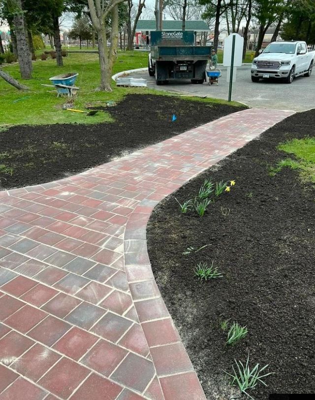 A brick walkway leading to a dumpster in a park