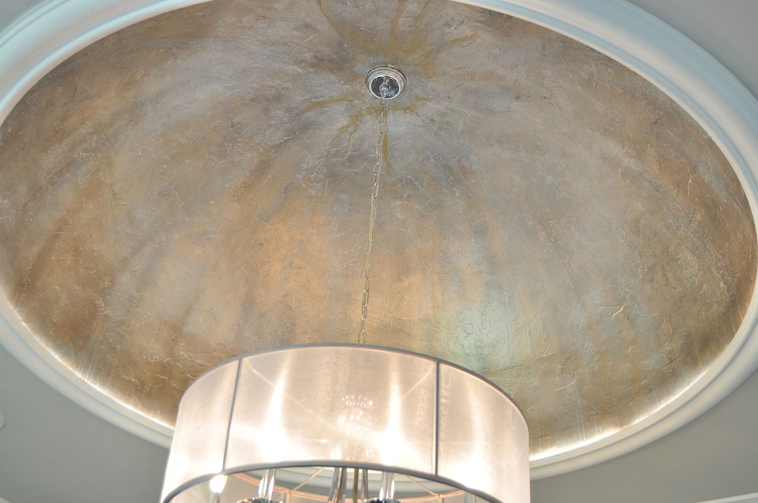 Gold-toned domed ceiling with recessed lighting. A large drum-shaped chandelier hangs below.