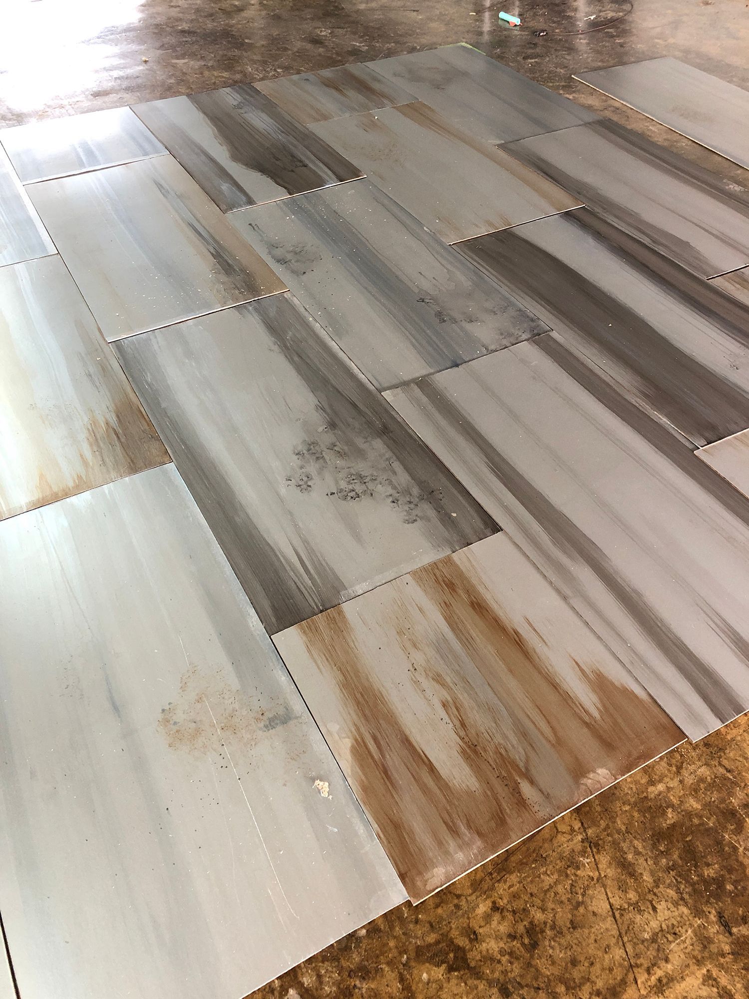 Floor tiles arranged in a staggered pattern, resembling wood planks; light blue, brown, and gray colors.