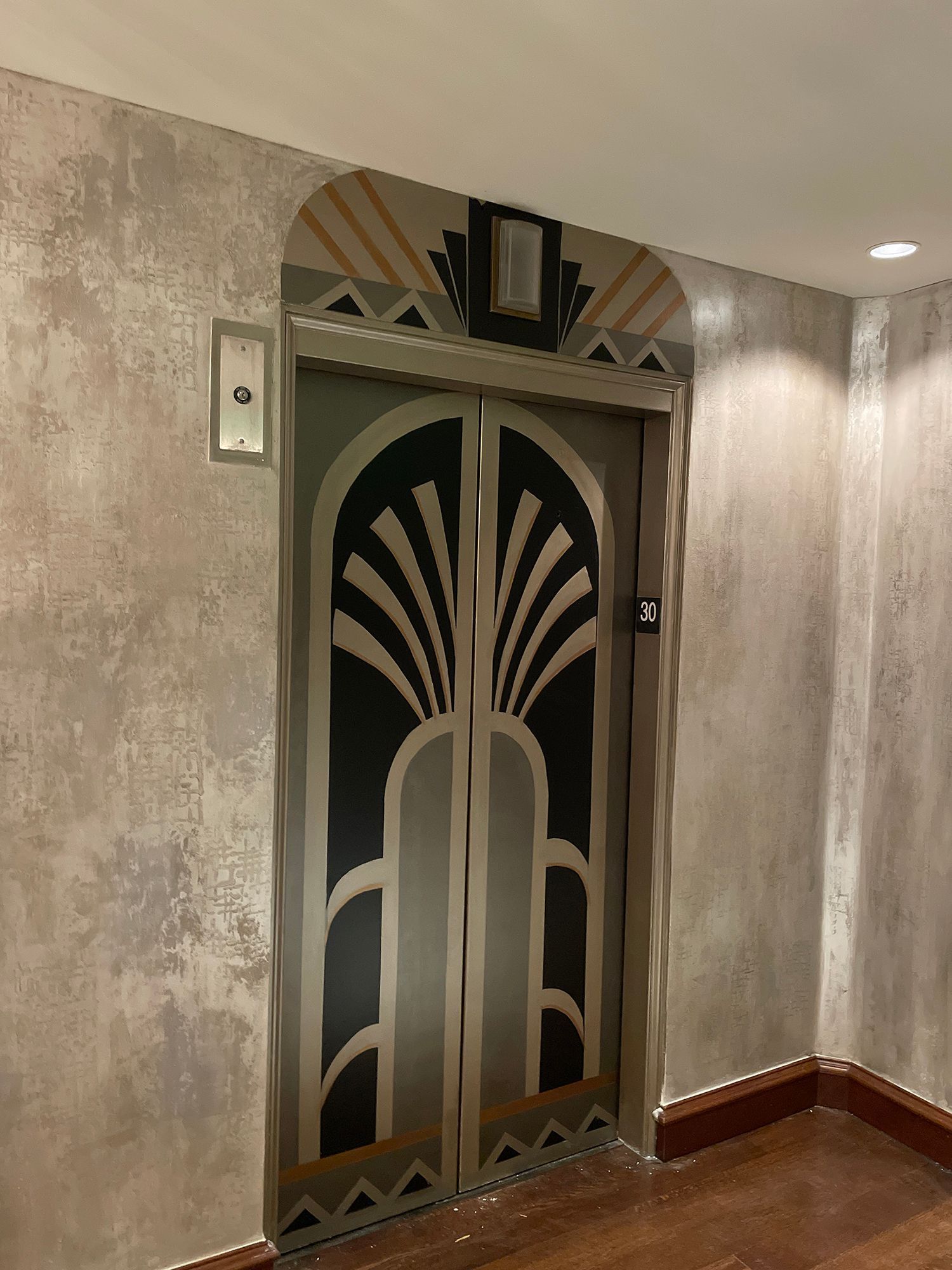 Art Deco elevator with ornate metal doors and decorative top panel.