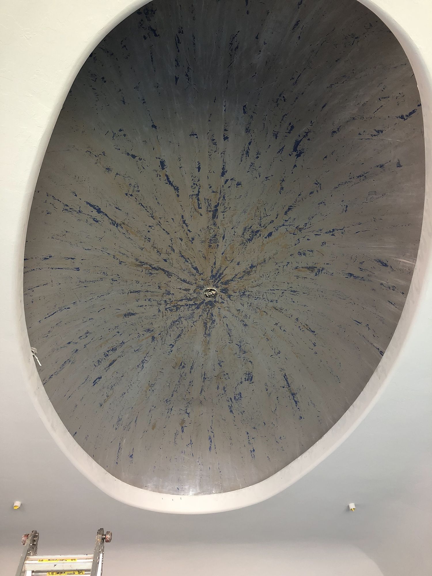 Oval ceiling inset, textured gray paint with dark bursts radiating from the center.