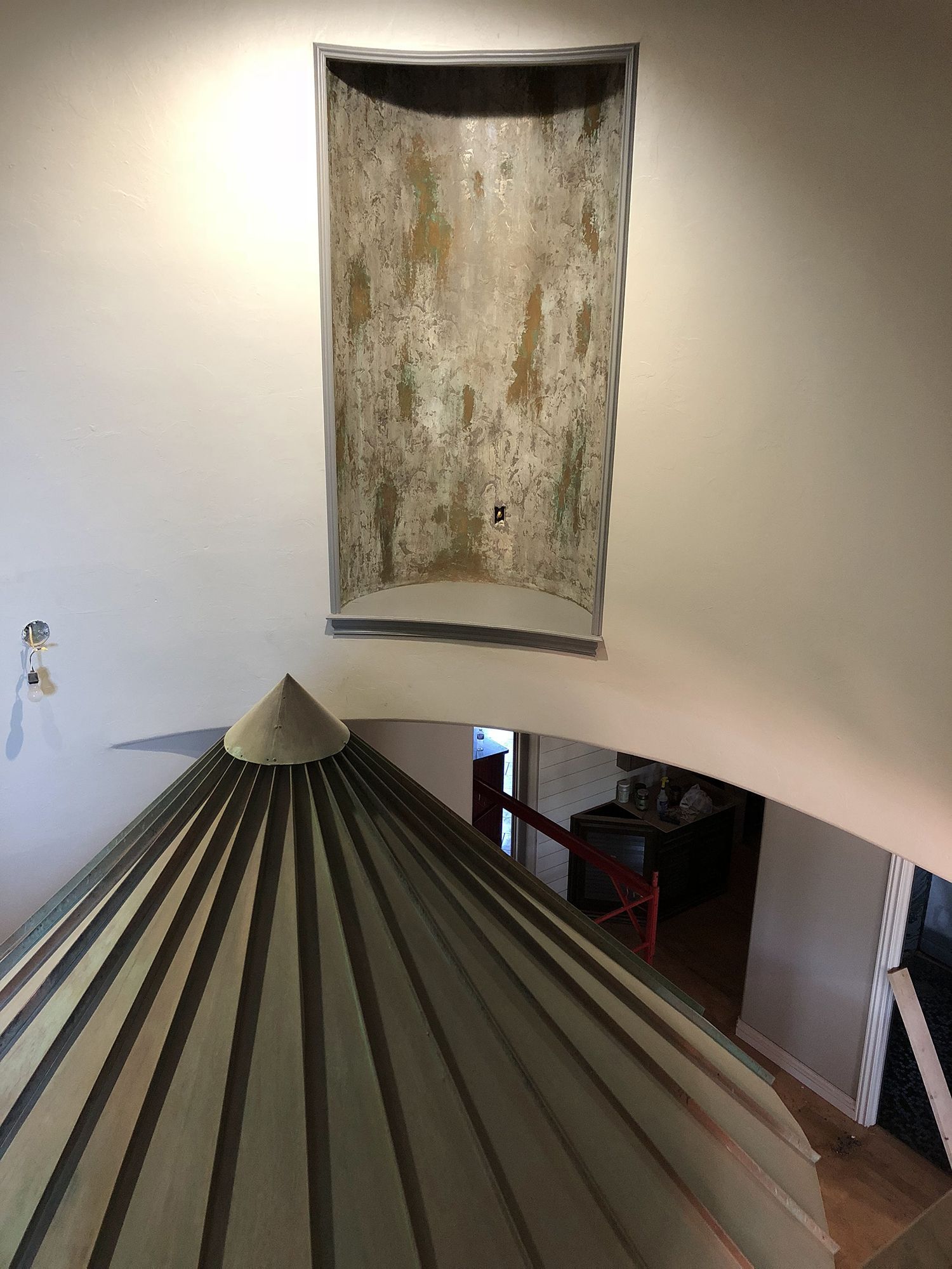 An overhead shot of a light-filled space. A peaked roof is below a rectangular wall niche with a textured surface.