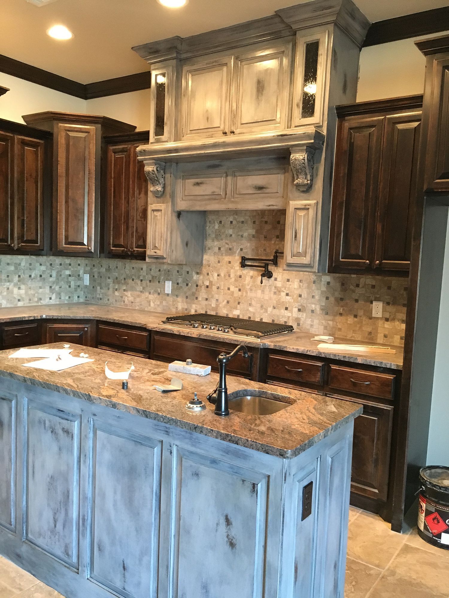Kitchen with a distressed white and brown cabinets and a stone backsplash.